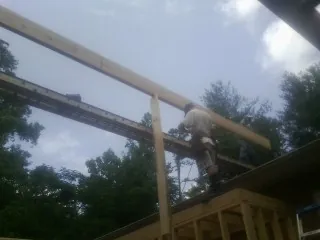Carpenter setting a ridge beam over a new addition frame — Ice Dam Removal by Roofing Brothers in Dallas