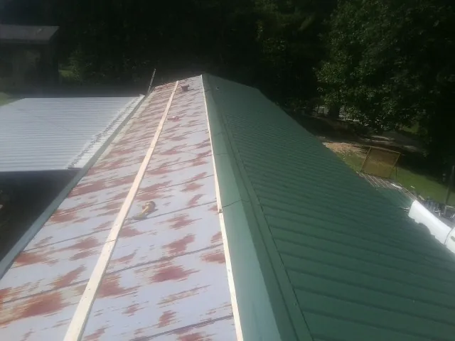 Old rusted panels beside newly installed green metal roofing — Wind Damage Roof Repair by Roofing Brothers in Dallas